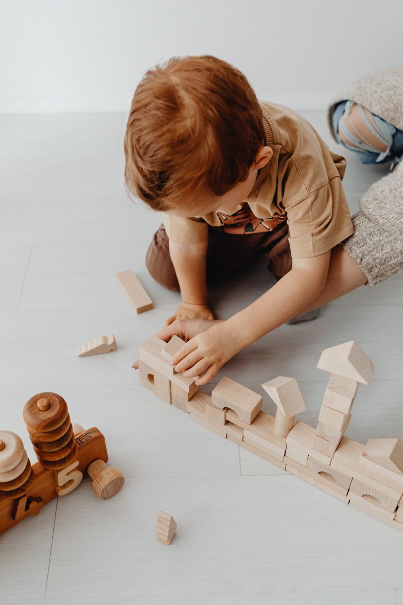 A young child playing with wooden educational toys on the floor at home.